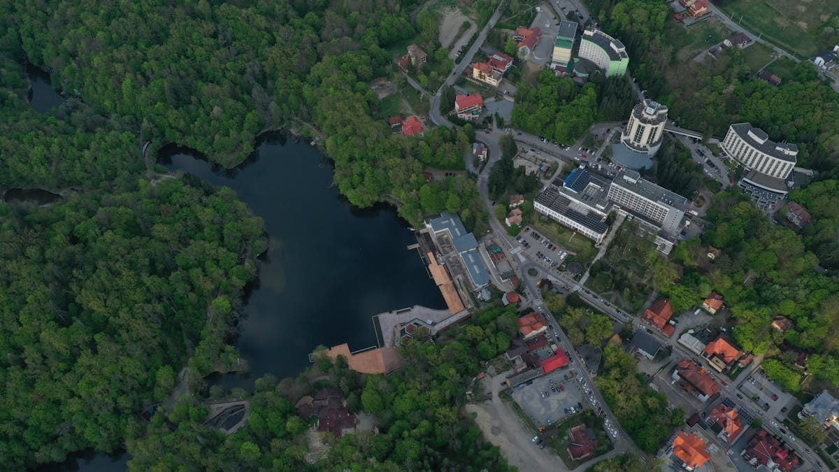 A breathtaking aerial view of Sovata, Romania, showcasing the serene lake surrounded by dense green forest and urban buildings.